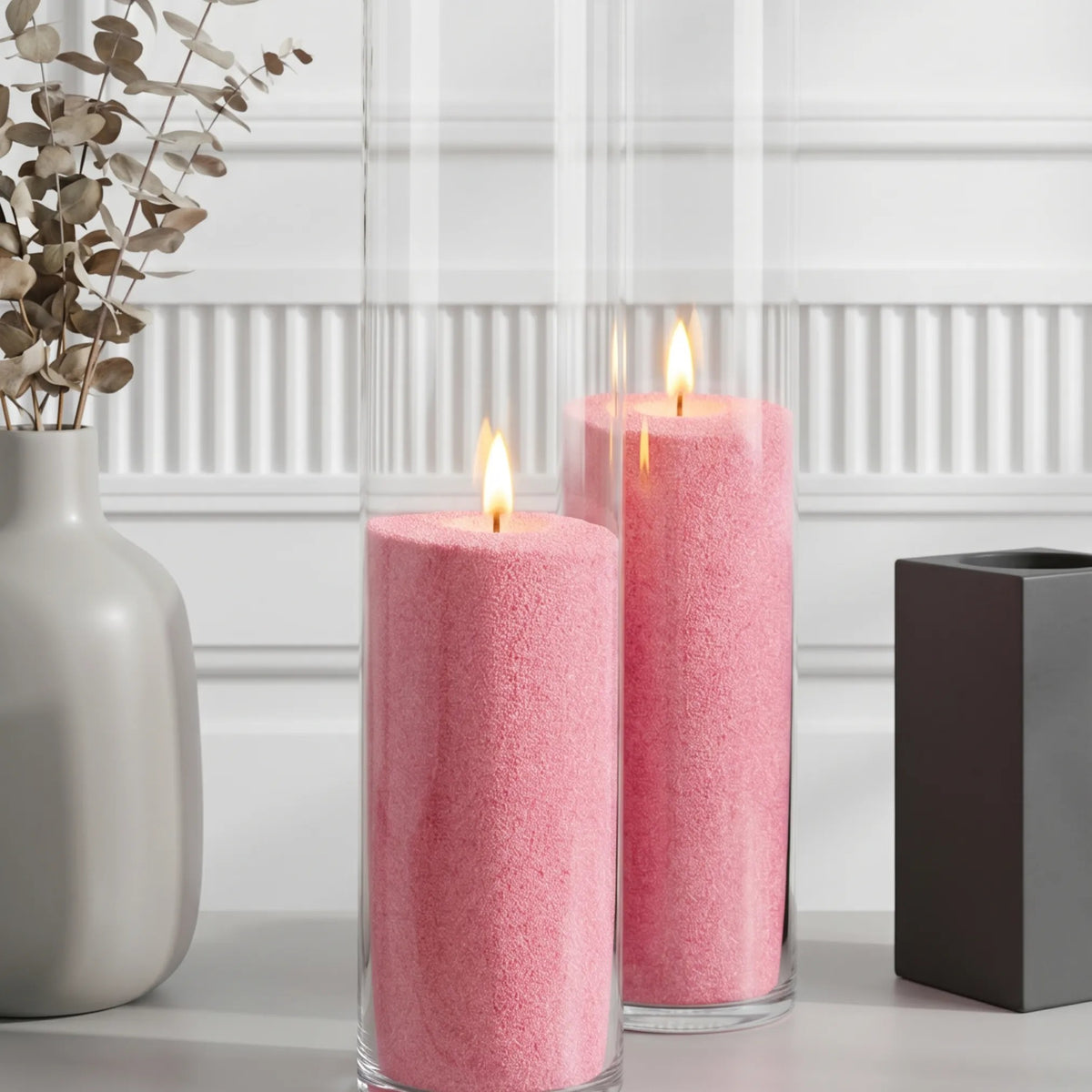 Two glass vases filled with burning Blush Vintage pearled candle sand 