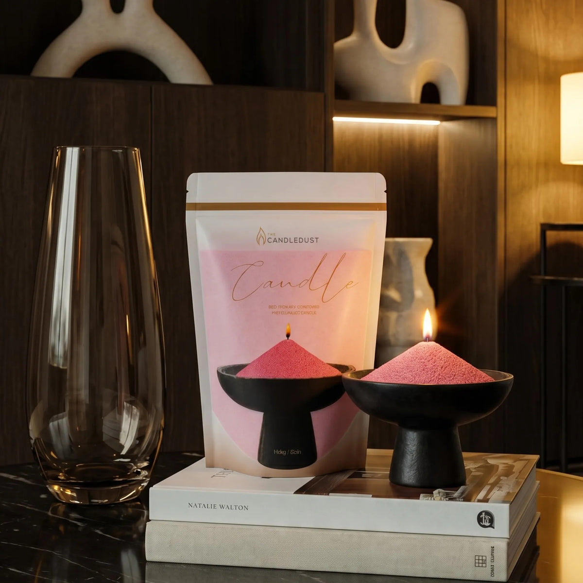 Lit Blush Vintage pearled sand candle displayed on a elegant vase with refill pouch resting on stacked books