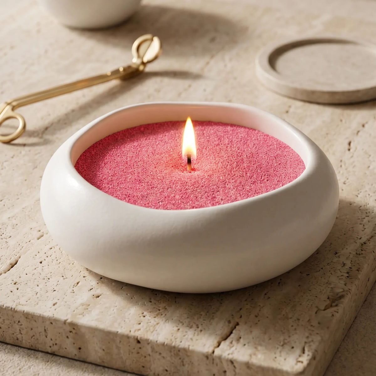 Lit Blush Vintage pearled sand candle displayed on a artistic vase resting on  a marble surface 