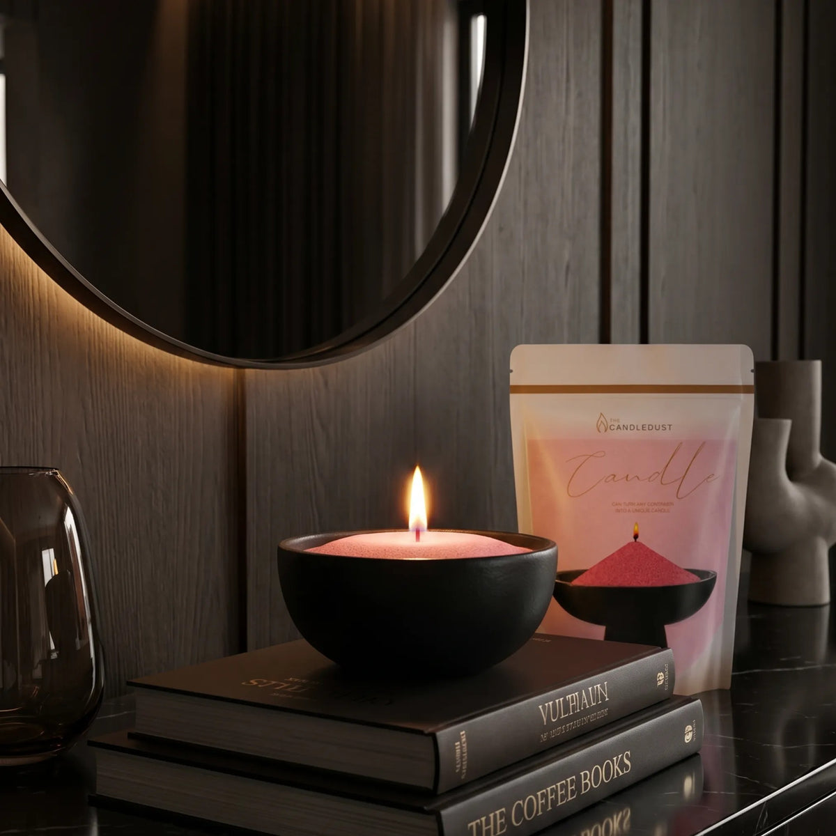 Lit Blush Vintage pearled sand candle displayed on a decorative vase resting on stacked books