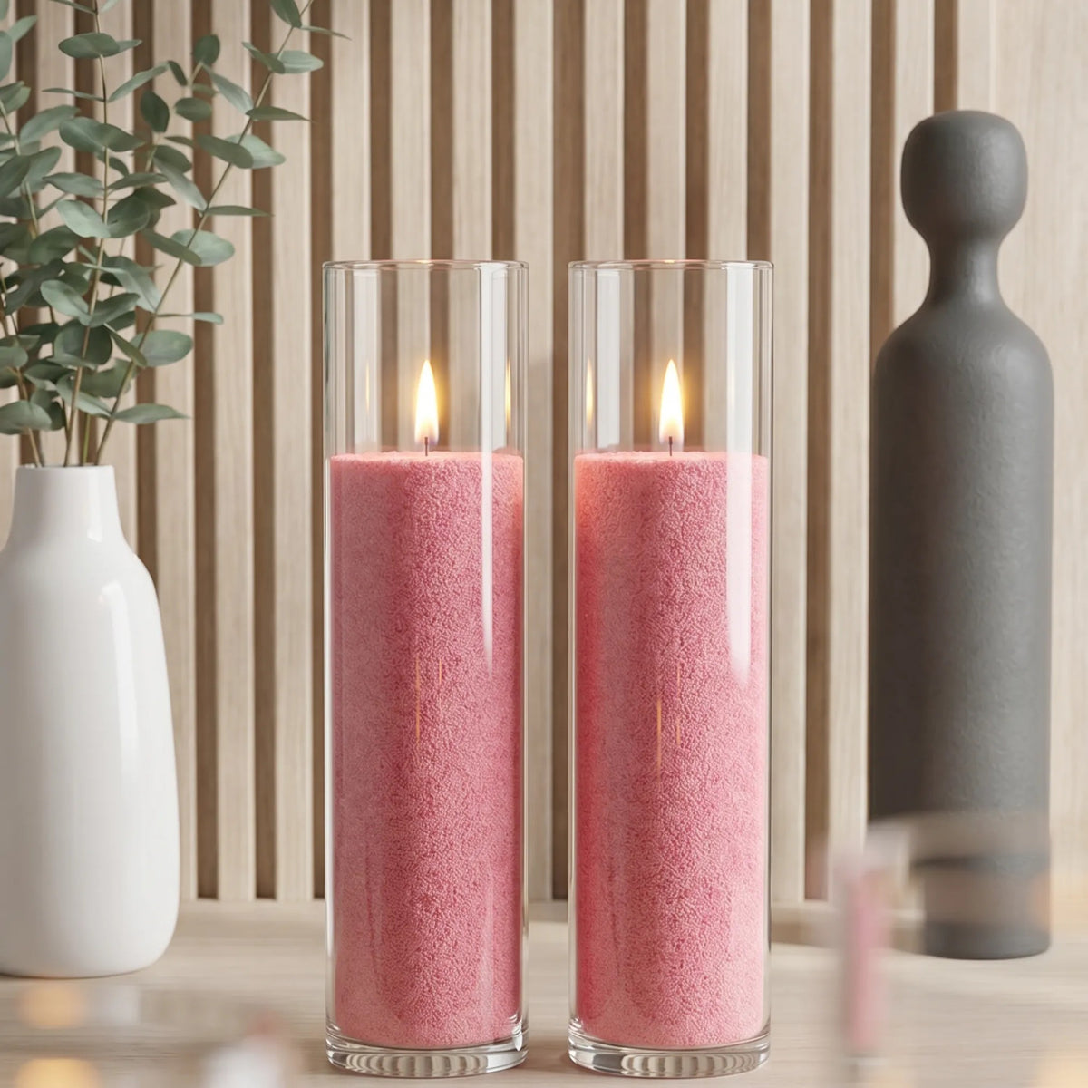 Two glass vases filled with burning Blush Vintage pearled candle sand creating a glowing cluster