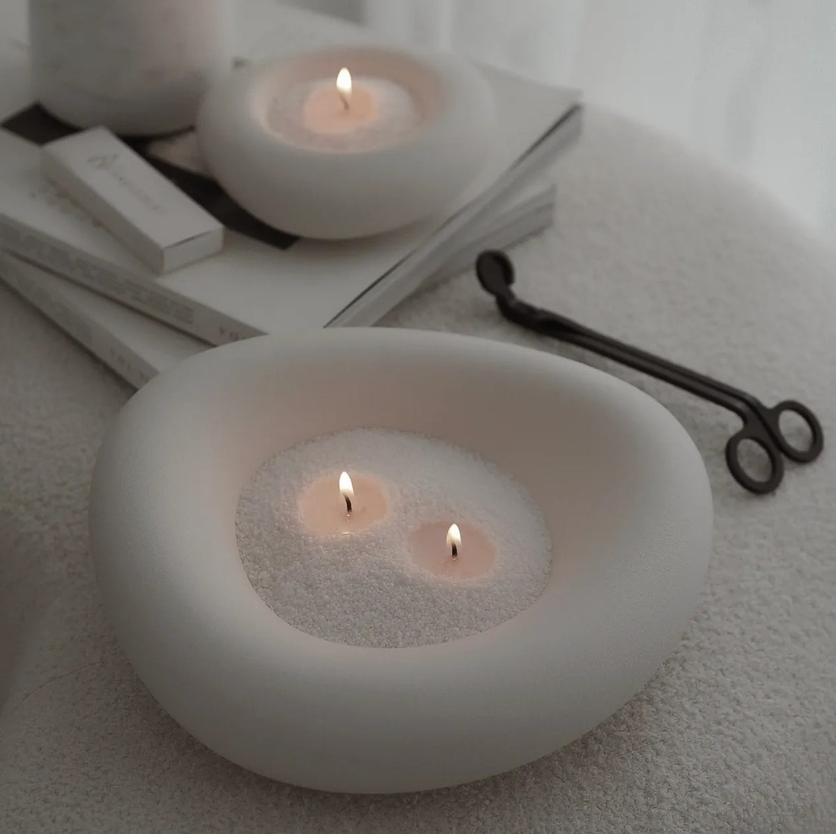 Elegant vase filled with Champagne Rhubarb scented pearled candle sand and lit cotton wicks resting on books 
