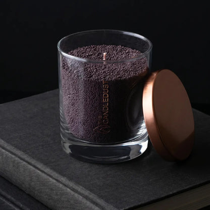 Candledust Dark Lilac unscented pearled candle in a 160g glass jar with cotton wick on a black book 