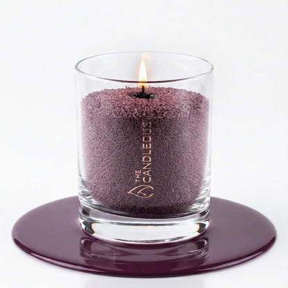 Close-up texture of natural plant-based Dark Lilac purple pearled candle wax granules inside a glass container