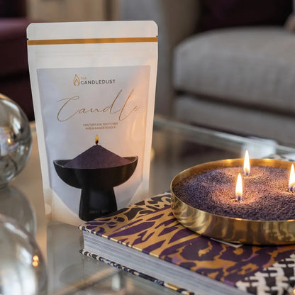 Lit Dark Lilac pearled sand candle displayed on a decorative tray resting on glass coffee table
