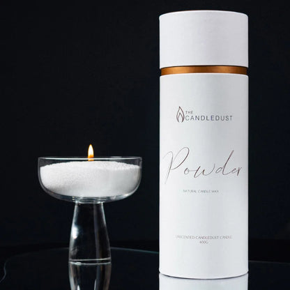 Candledust Dark Honey candle sand tube and lit glass candle against a black background
