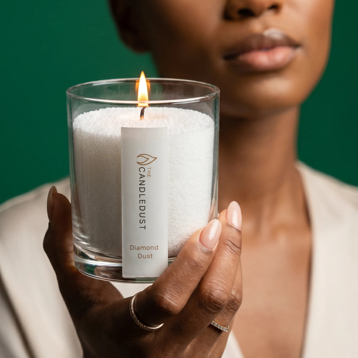 Woman holds lit Candledust Diamond Dust scented pearled candle in a 160g glass