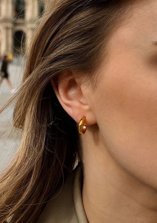 Close-up of a model wearing the stylish gold Ella Hoops Earrings.