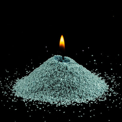 Burning Emerald pearled sand candle with a bright flame isolated on a dramatic black background