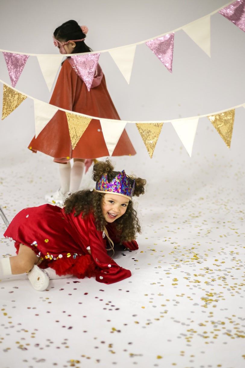 Party time: joyful children playing and laughing under a shimmering gold and beige Sequin Garland in a bright nursery