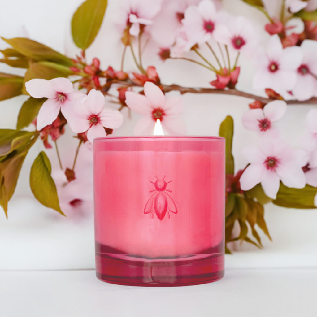 Lit La Rochère Cherry Blossom scented candle glowing warmly beside a decorative branch with spring blossoms
