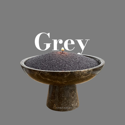 Grey text on a matching elegant grey background with a glass vase full of unlit pearled candle sand in the foreground
