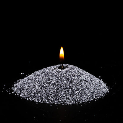 Burning Grey pearled sand candle with a bright flame isolated on a dramatic black background