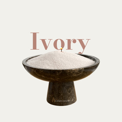 Ivory text on a matching warm ivory background with a glass vase full of unlit pearled candle sand in the foreground