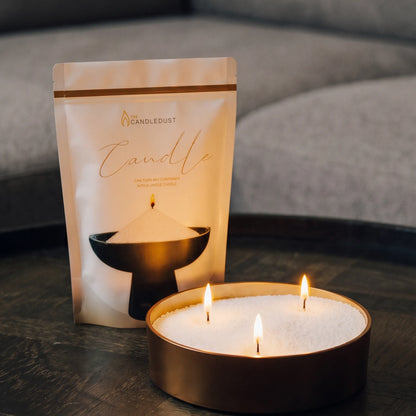 Lit Ivory pearled sand candle and pouch displayed on a decorative tray resting on a dark table