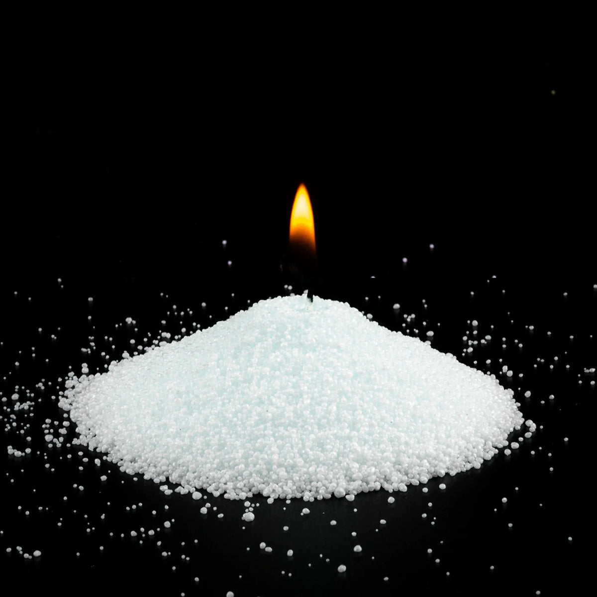 Burning Lemongrass Ginger scented pearled sand candle with a bright flame isolated on a dramatic black background