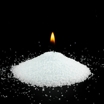Burning Lemongrass Ginger scented pearled sand candle with a bright flame isolated on a dramatic black background