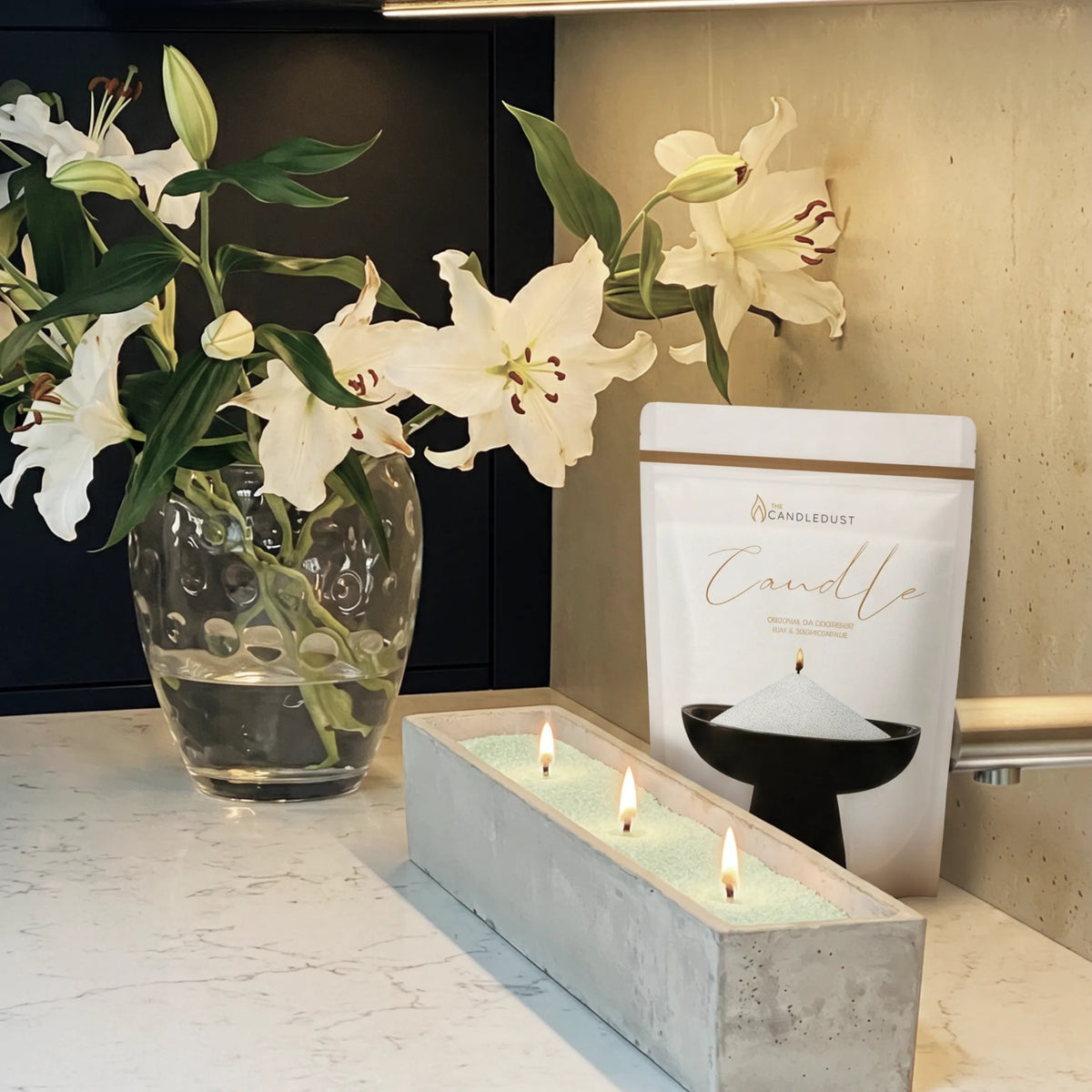 Marble vase filled with Lemongrass Ginger scented pearled candle sand and lit cotton wicks on a refined marble surface
