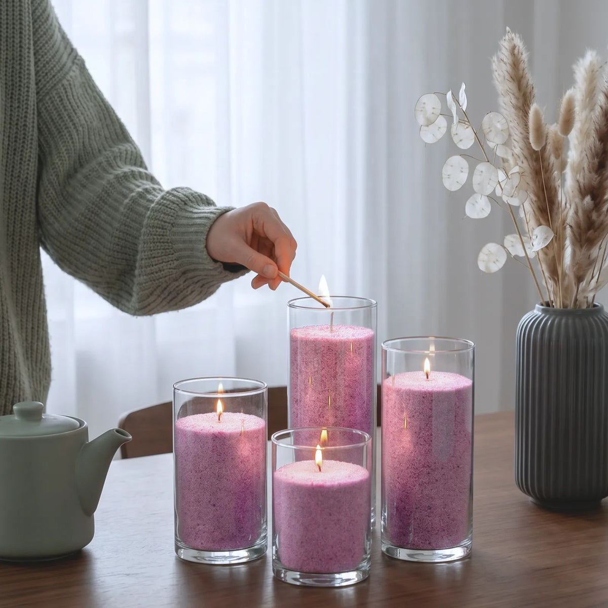 woman's hand lighting the cotton wick of a Candledust Lilac unscented pearled candle sand