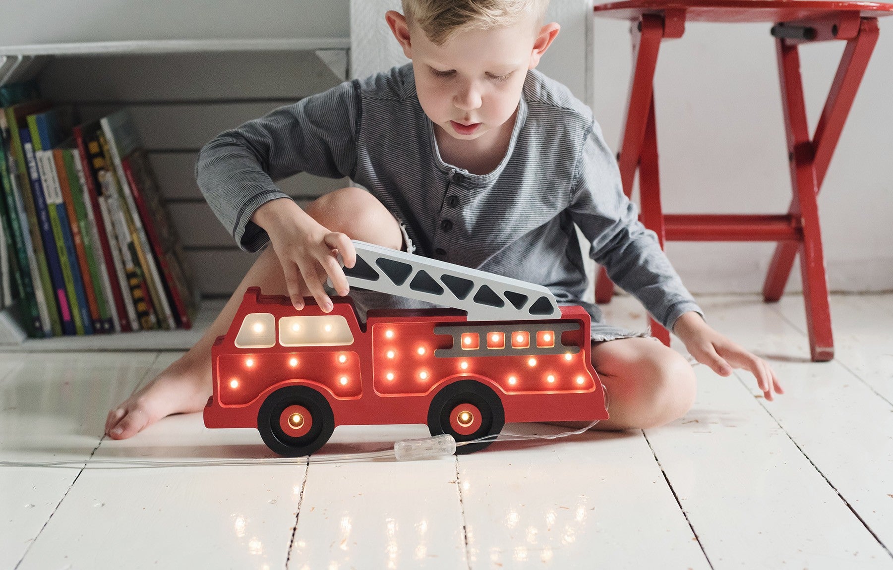 Kid playing with Little Lights firetruck shaped wall lamp glowing in the dark