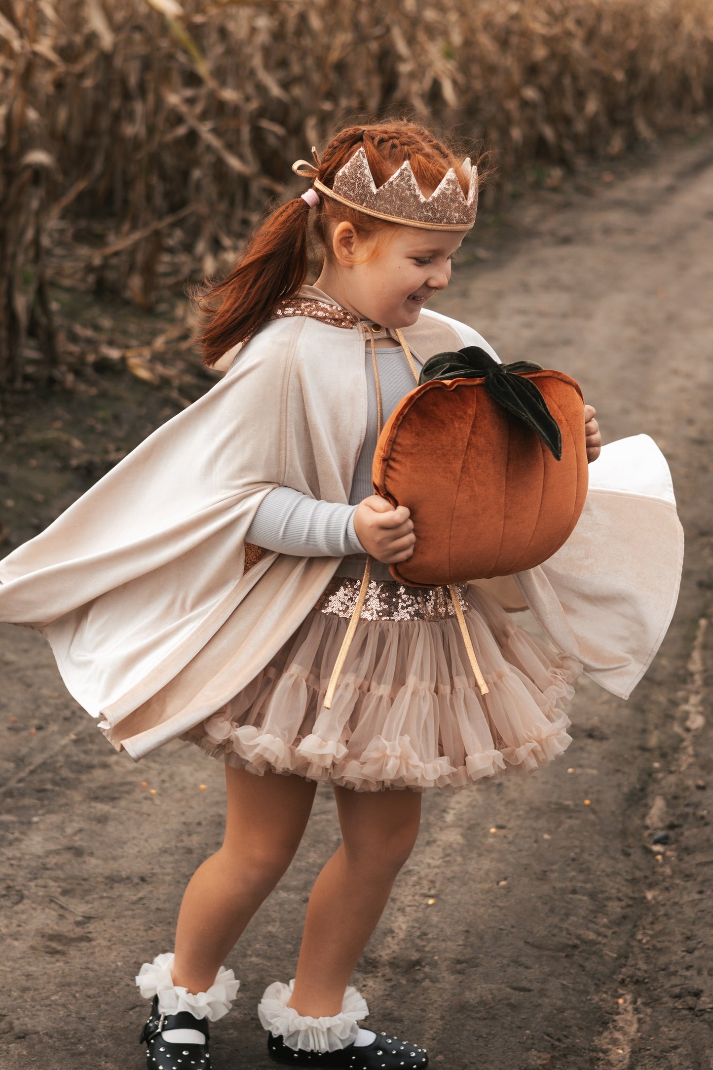 Nature adventures: child in Cream Pearl cape exploring a sunlit forest path during autumn