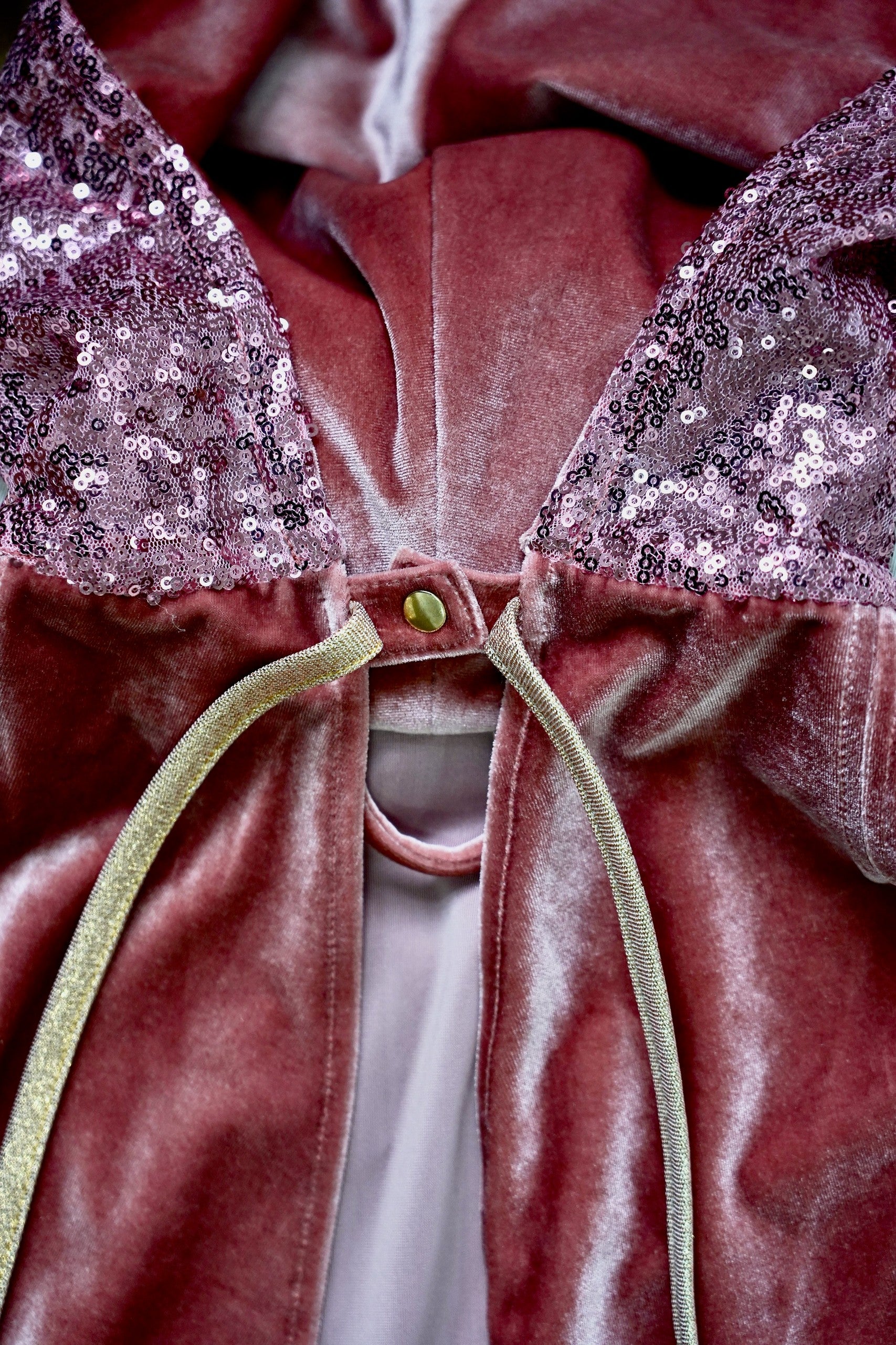 Detailed view of the pink velvet fabric and secure snap fastening on the cape