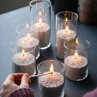 Close-up of a woman's hand lighting the cotton wick of a Midnight scented pearled sand candle