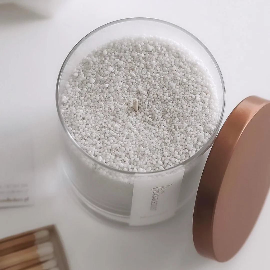 Close-up texture of natural plant-based Midnight scented pearled candle wax granules inside a glass container