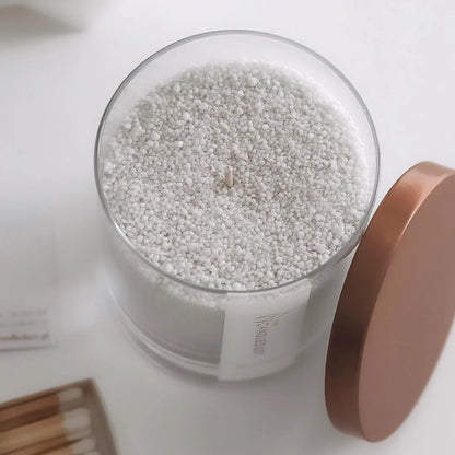 Close-up texture of natural plant-based Midnight scented pearled candle wax granules inside a glass container
