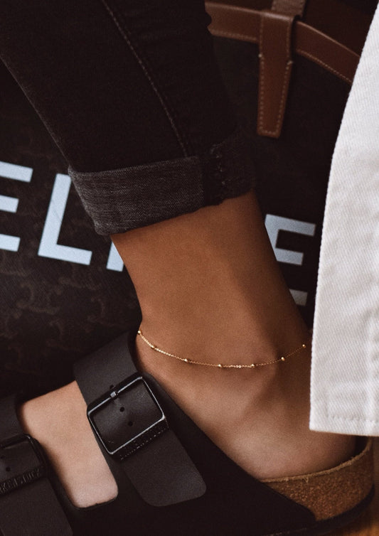 A model enjoying a sunny day, highlighting the gold Mini Bubble Anklet.