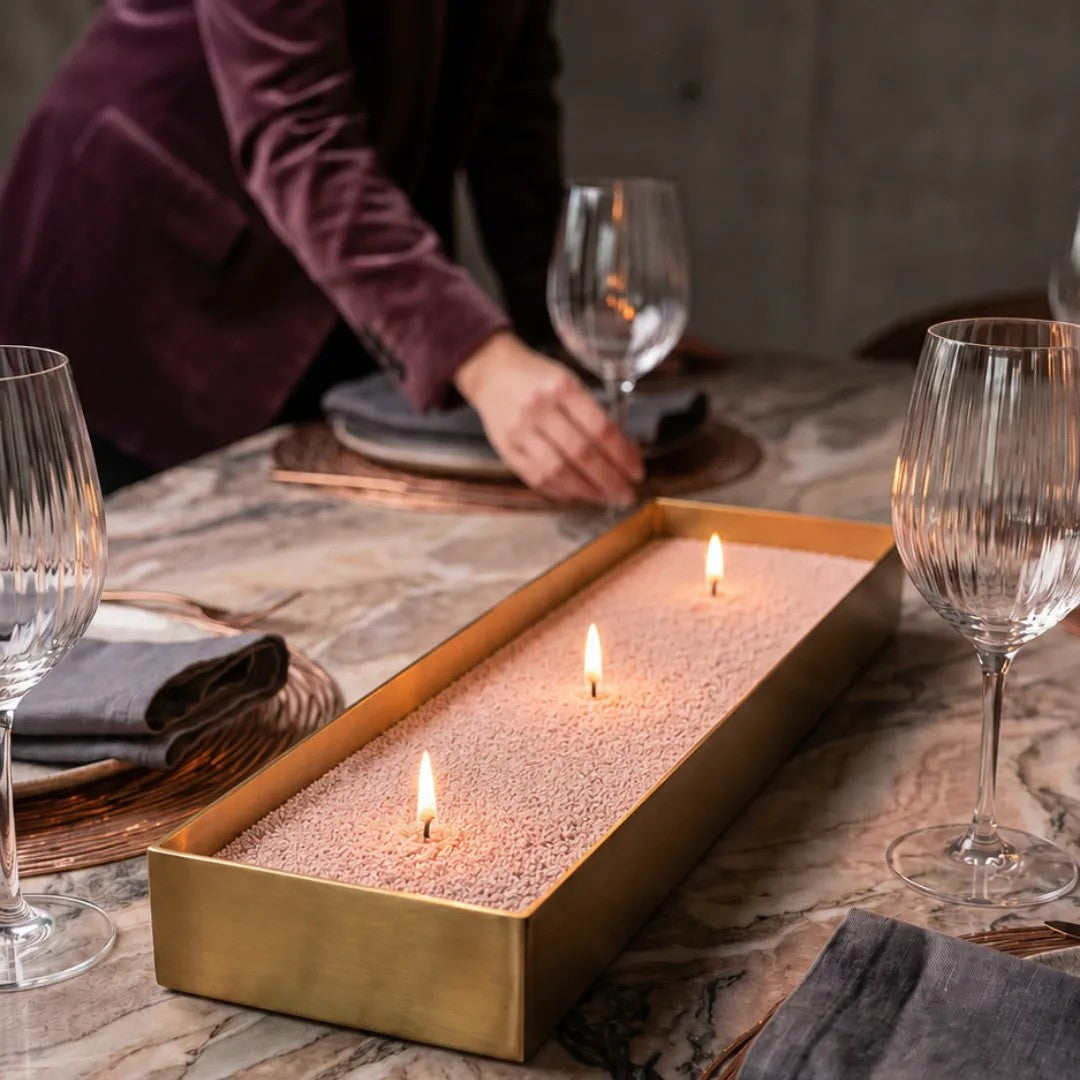 Elegant marble table featuring a center brass tray filled with burning Mocha Mousse pearled sand candles
