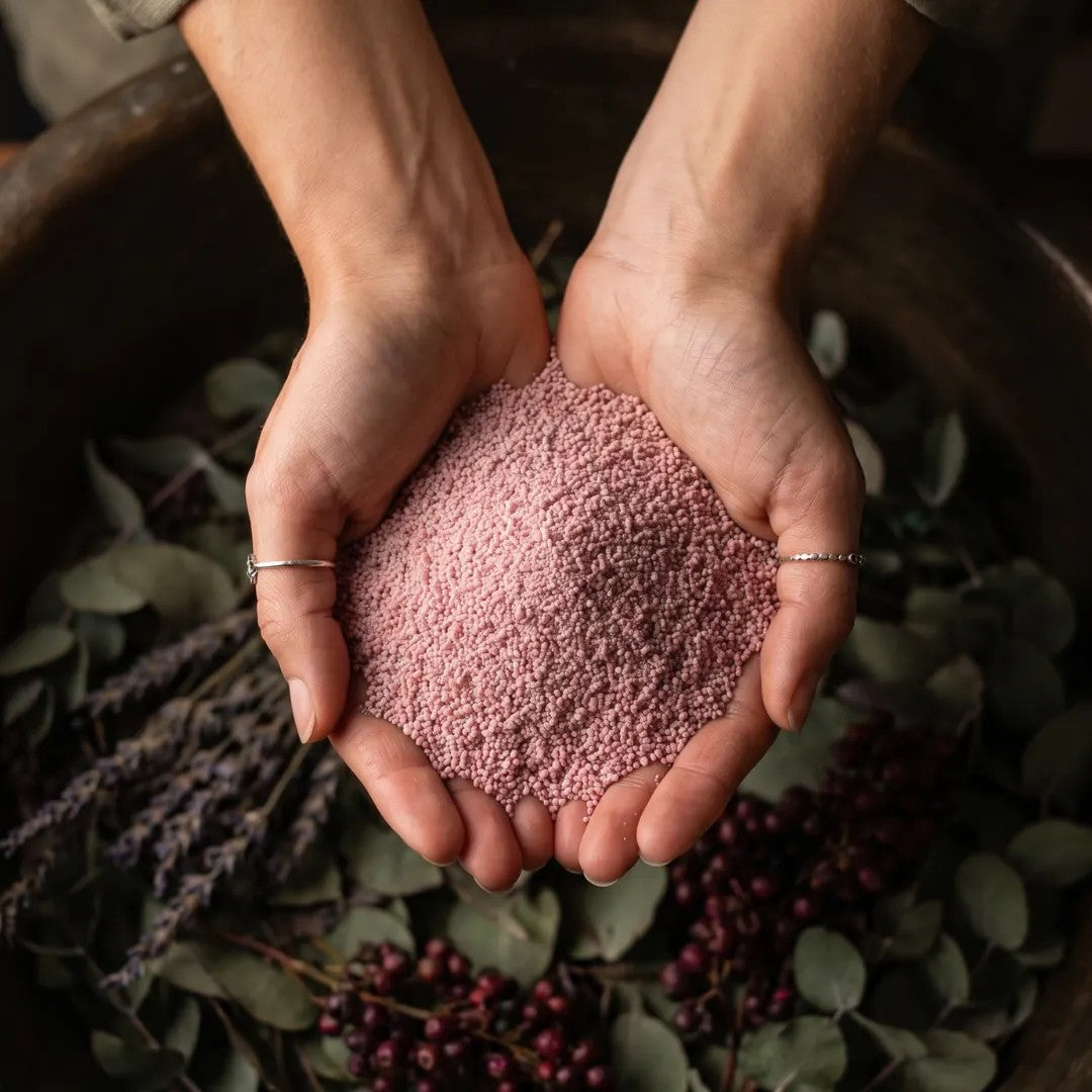 Mocha Mousse pearled candle wax granules held in cupped hands over a garden planter vase