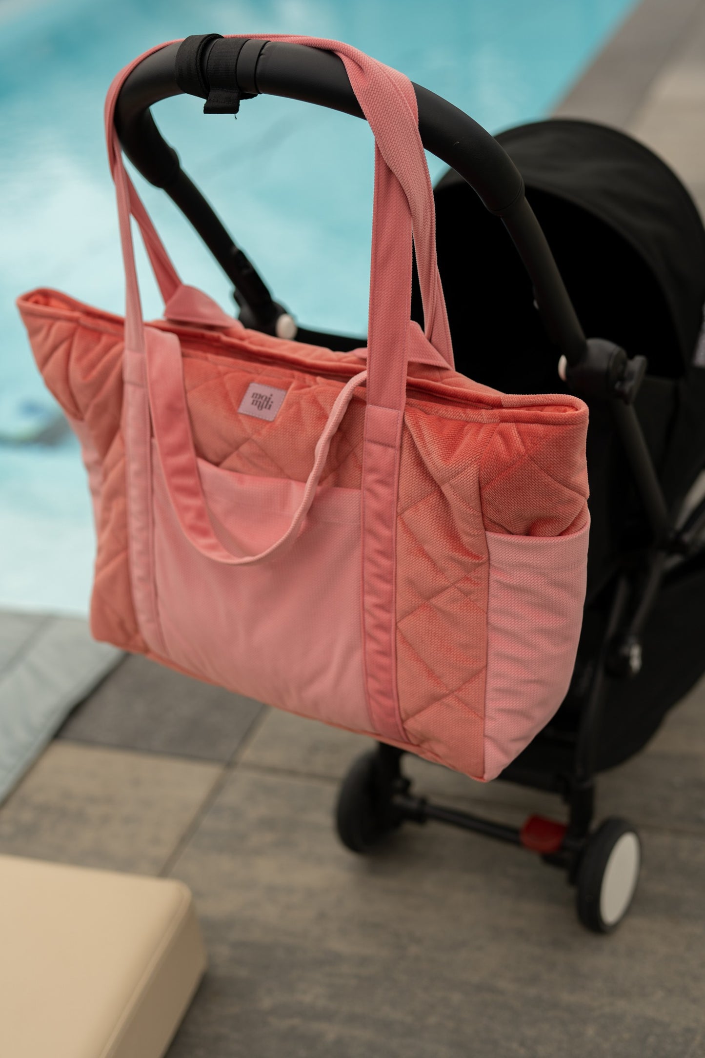Moi Mili Candy Mom Weekender Bag: pink quilted cotton travel bag attached to a modern stroller handlebar
