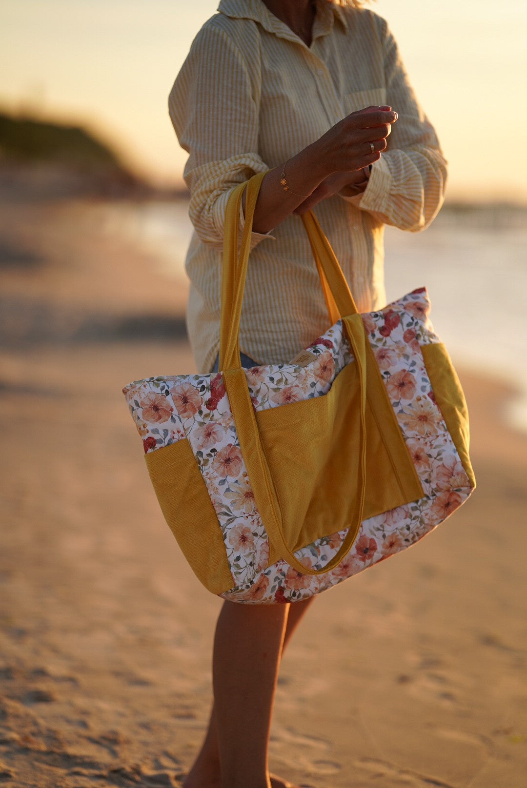 Beach life: a mother holding a sturdy Flower Power cotton travel bag during a family walk by the sea at sunset