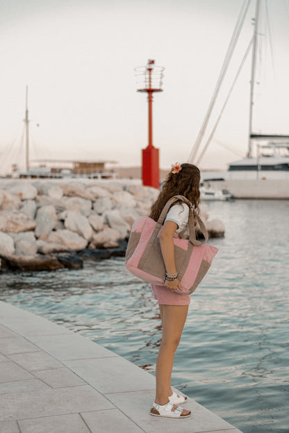 Moi Mili Mom Weekender Bag Pink Coffee: a young woman walking along a wooden dock carrying a large quilted cotton travel bag