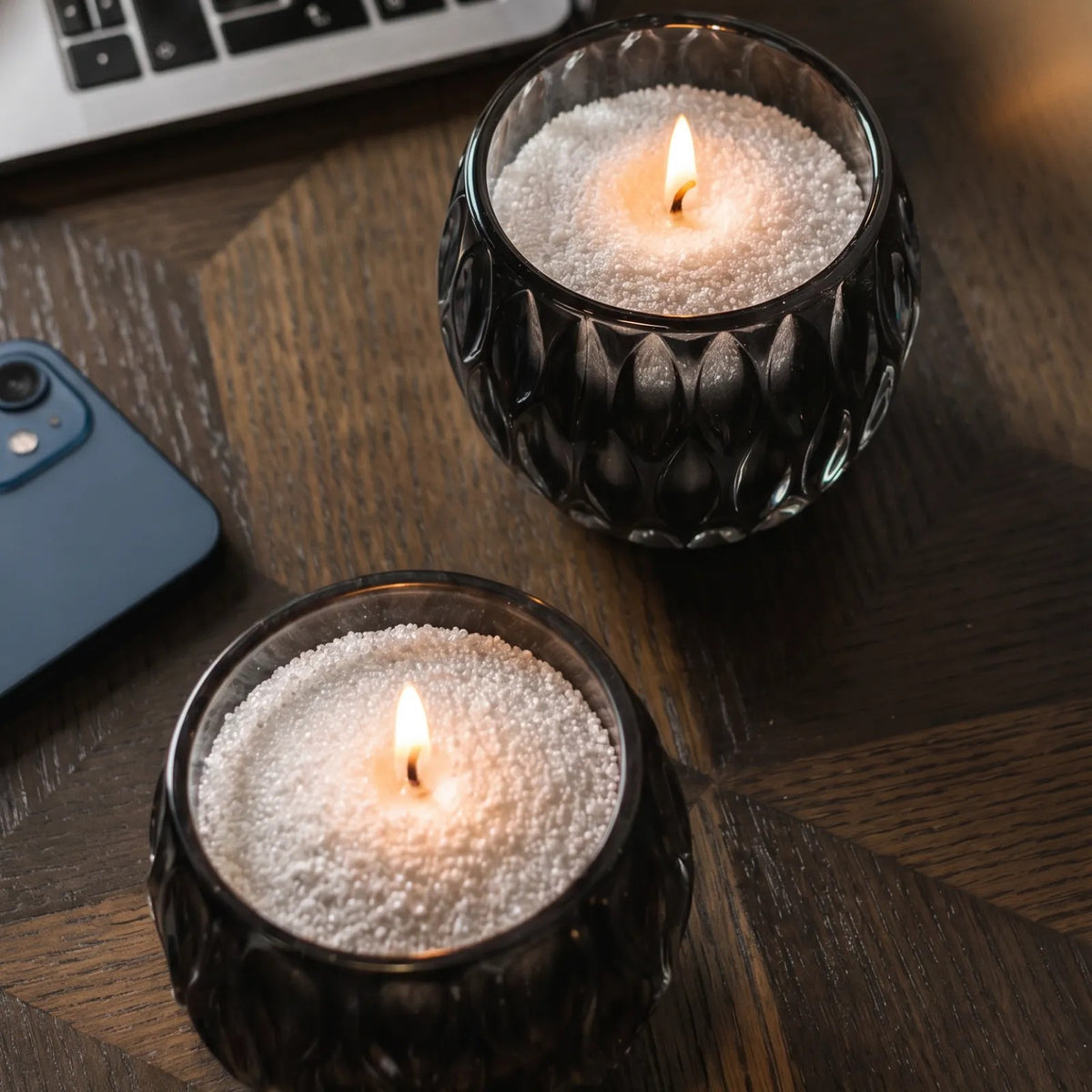 Glass vases filled with burning Nordic Lights pearled candle sand on a wooden table