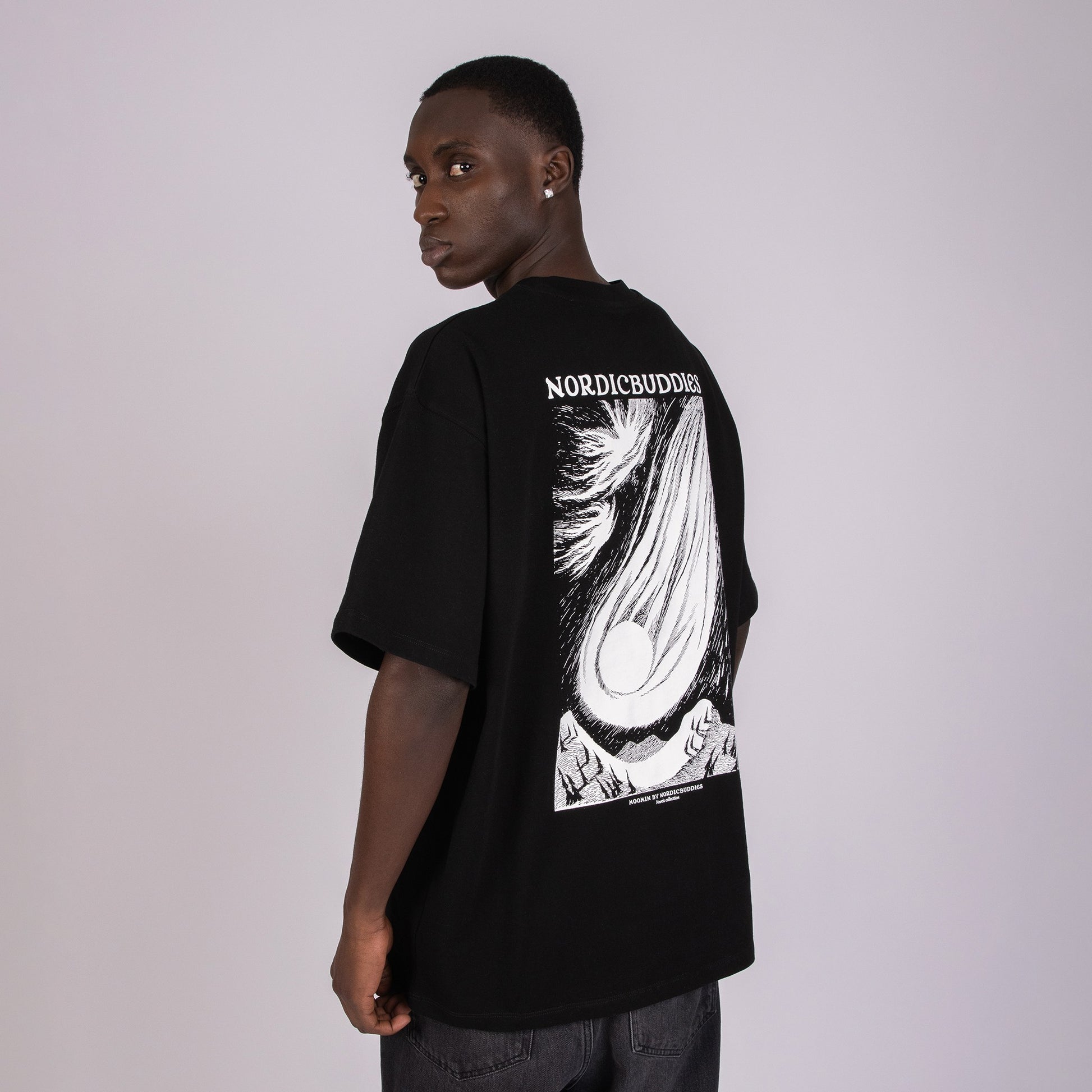 Person wearing a black t-shirt with a white Moomin graphic design on the back against a plain background