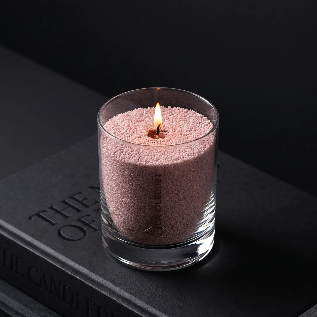 Lit Candledust Nude unscented pearled candle in a 160g glass jar on a book