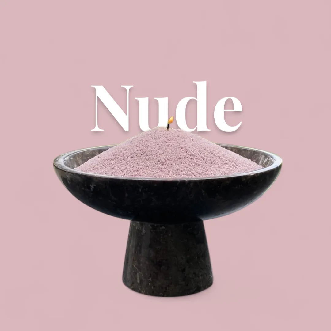 Nude text on a matching neutral nude background with a glass vase full of unlit pearled candle sand in the foreground