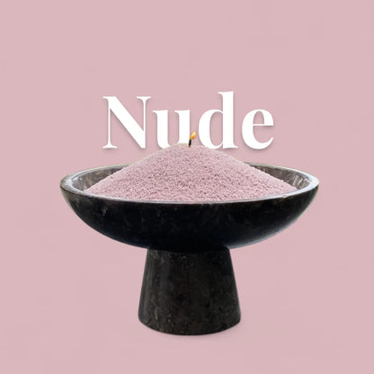 Nude text on a matching neutral nude background with a glass vase full of unlit pearled candle sand in the foreground