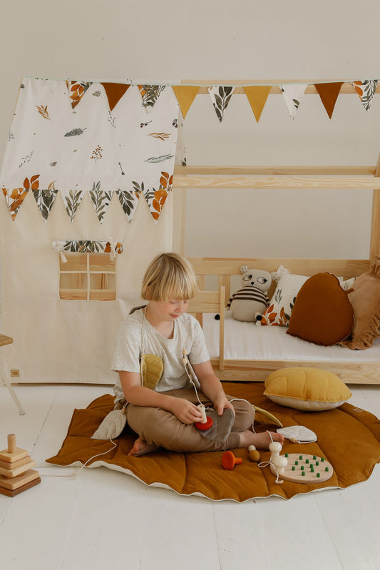 Playtime: a kid playing with wooden toys on the large Caramel linen leaf-shaped mat