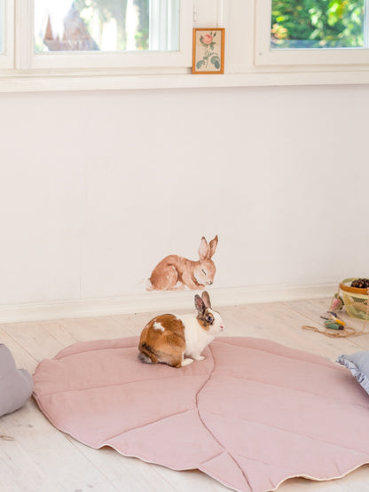 Moi Mili Powder Pink Leaf Playmat: a fluffy bunny rabbit resting on a soft quilted linen leaf-shaped baby mat