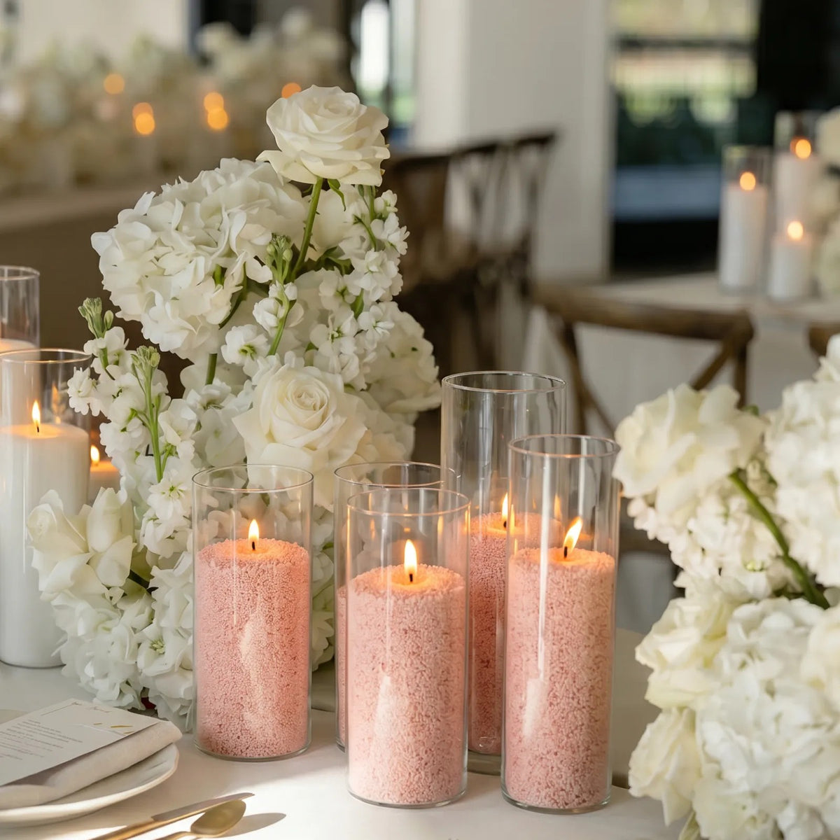 Elegant dining table beautifully set for a dinner party with a glowing Peach glass sand candle at each place setting