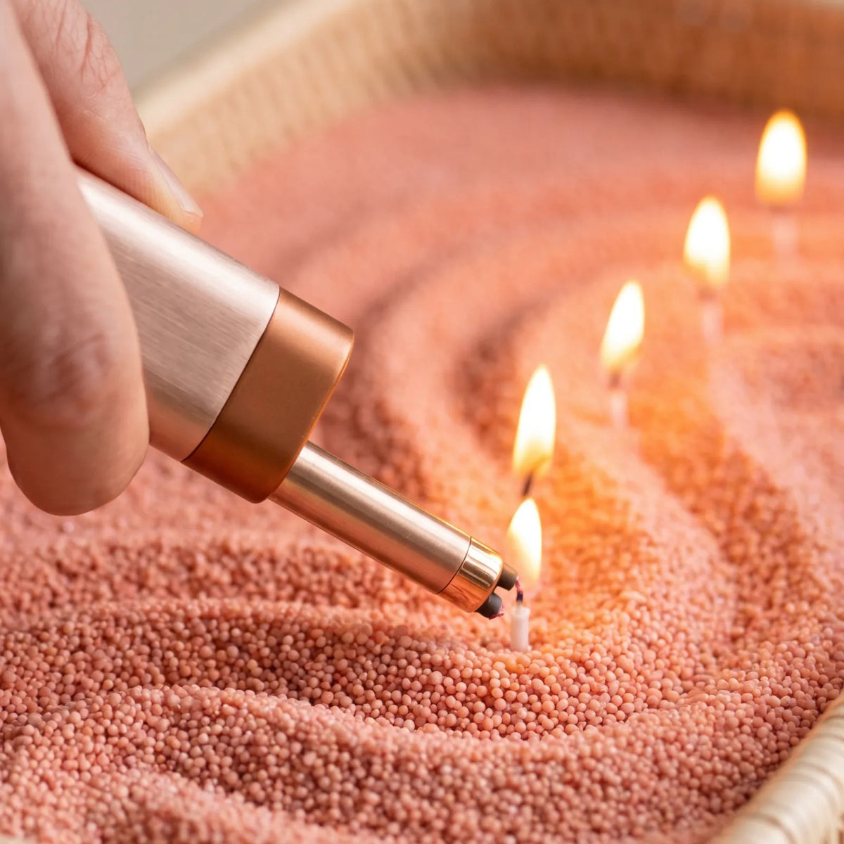 Close-up of a woman's hand lighting the cotton wick of a Peach pearled sand candle