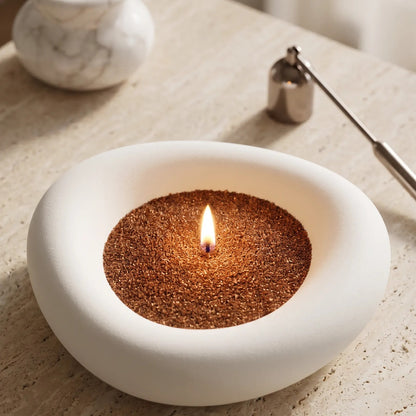 Elegant marble vase filled with Pecan pearled candle sand and lit cotton wick resting on a refined marble countertop