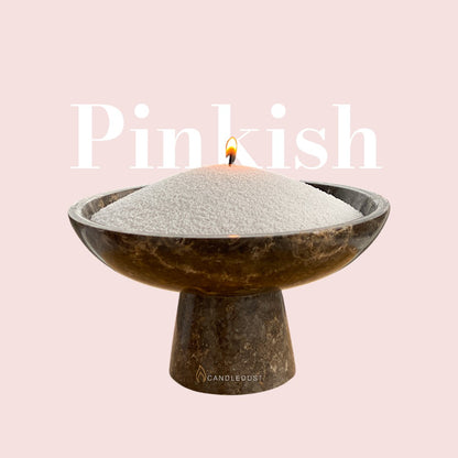 Pinkish text on a matching soft pinkish background with a glass vase full of unlit pearled candle sand in the foreground