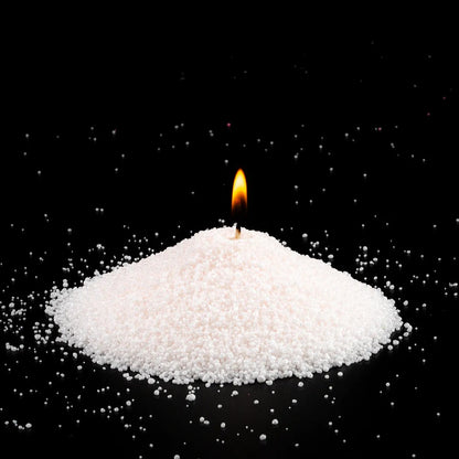 Burning Pinkish pearled sand candle with a bright flame isolated on a dramatic black background