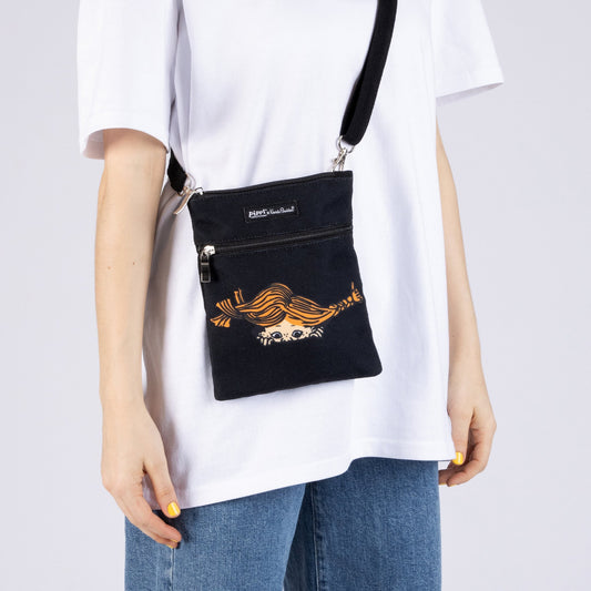 Person wearing the black Pippi Longstocking crossbody passport bag in a casual travel setting