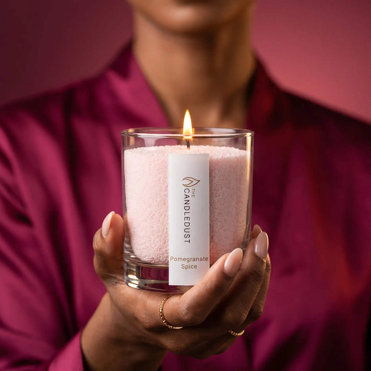 Female model holds a lit Candledust Pomegranate Spice scented pearled candle in a 160g glass jar