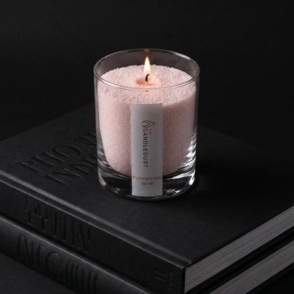 Lit Pomegranate Spice scented pearled glass candle resting on stacked books